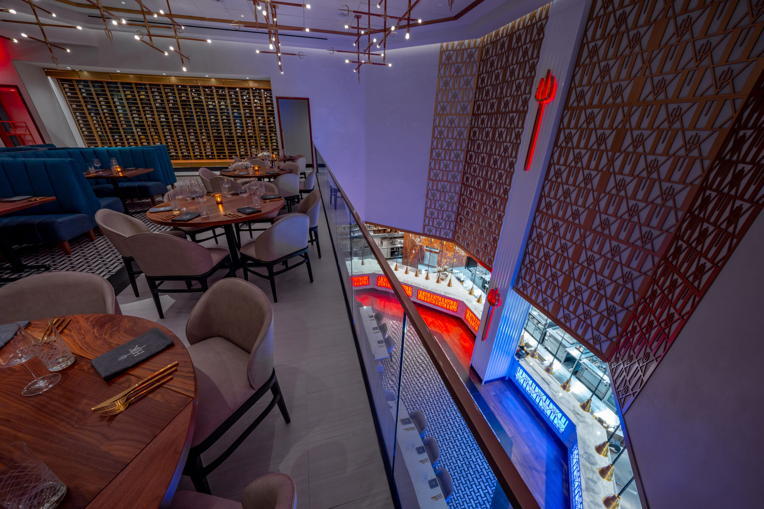 A multi-storey restaurant dining room with a wine cellar, viewed from an upper balcony.