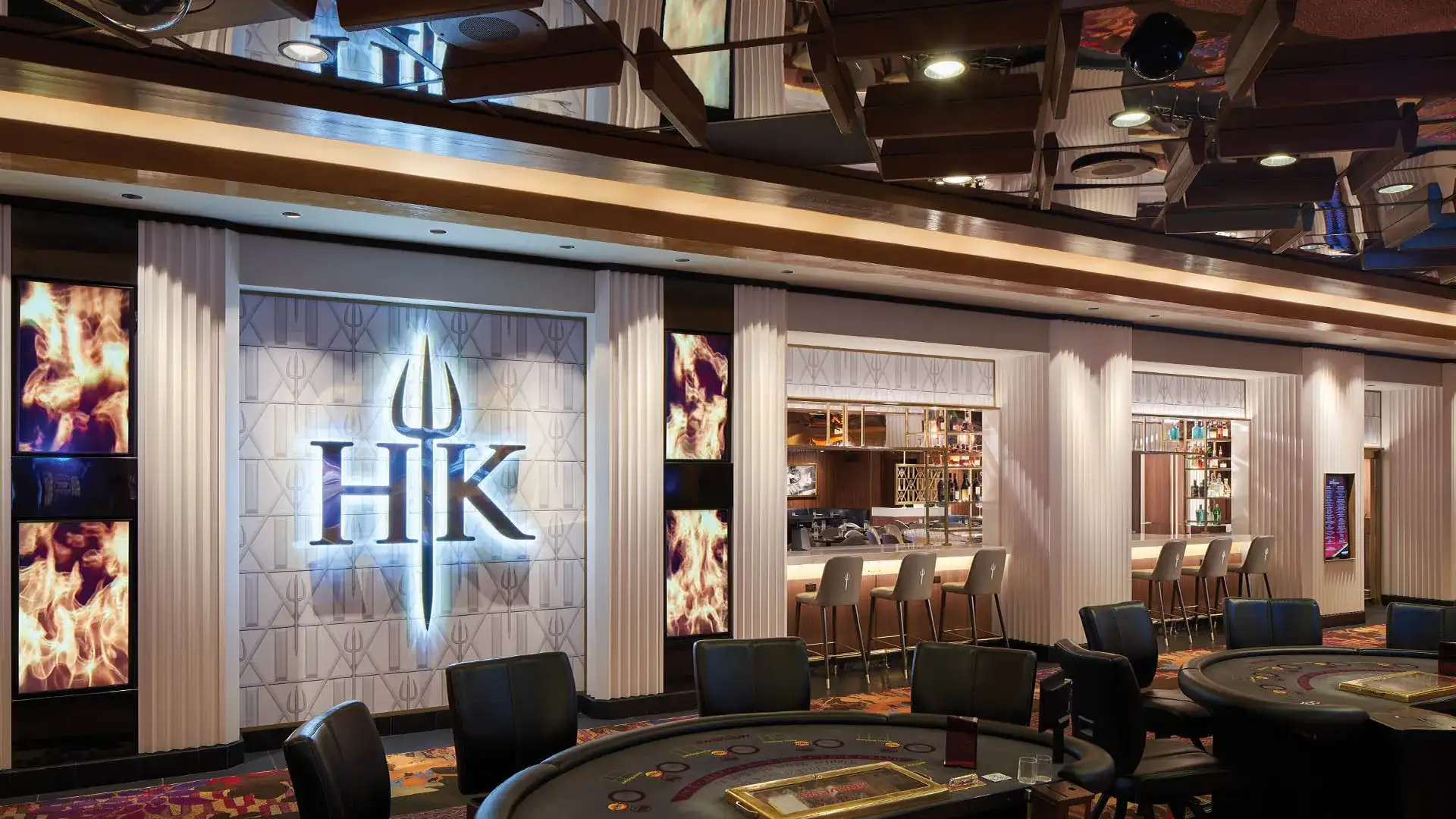 Hell’s Kitchen restaurant interior featuring a bar with high stools and gaming tables in the foreground.