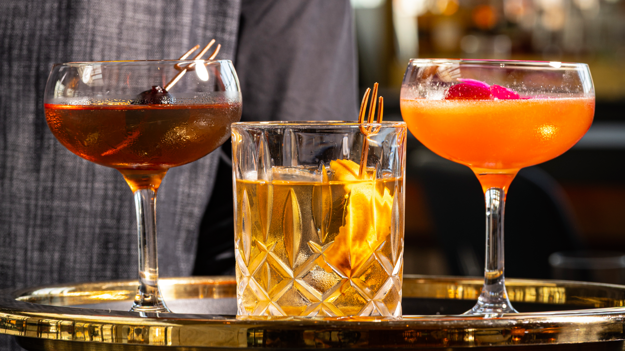 Three different cocktails on a golden tray.
