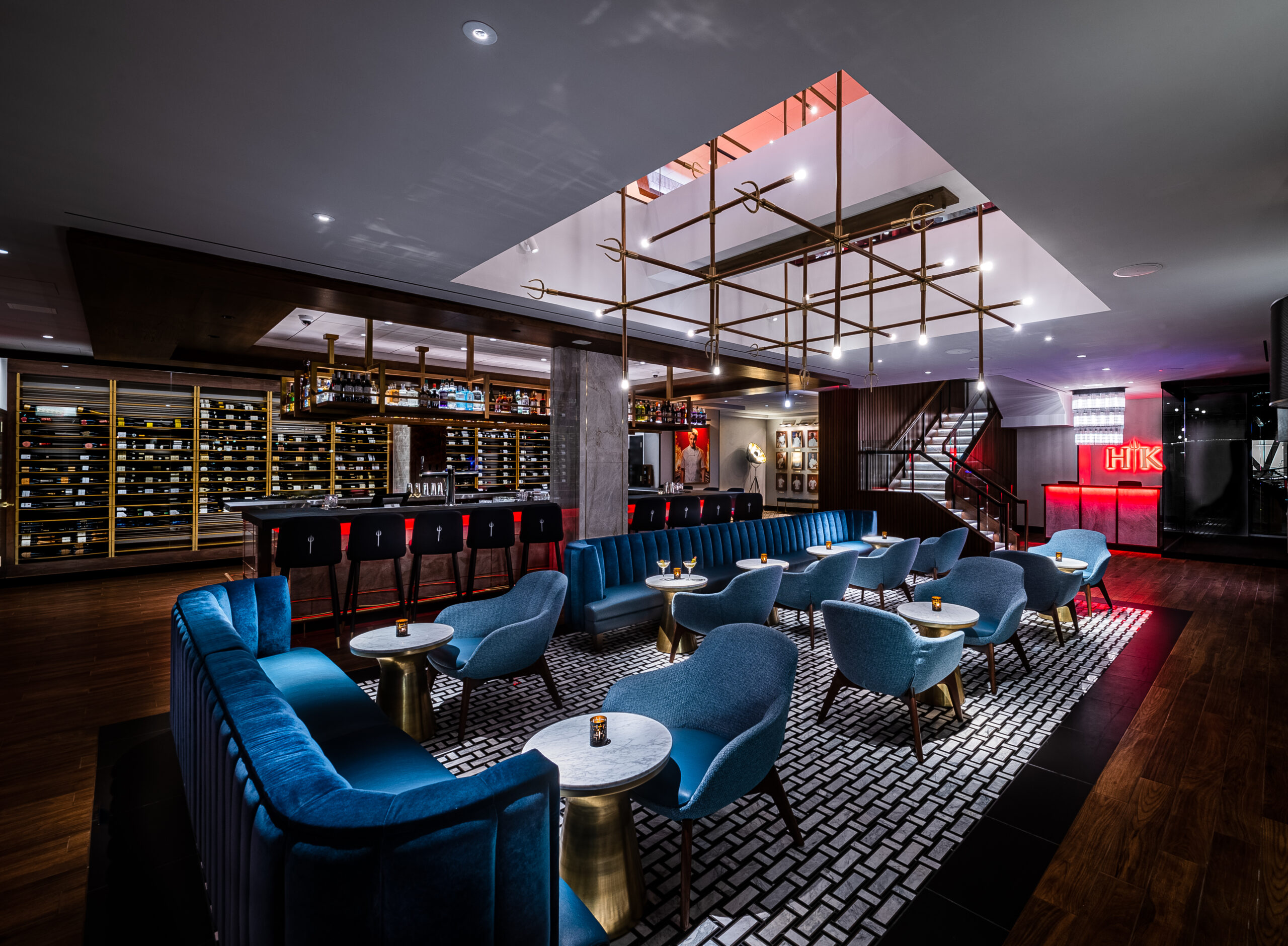 Upscale lounge with blue velvet booths, small tables, and a backlit bar area.