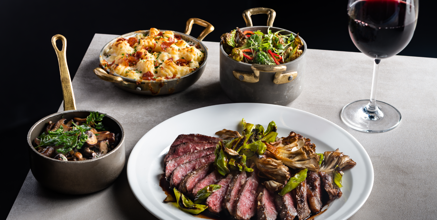 Sliced steak with mushrooms and greens, Hell’s Kitchen sides of macaroni cheese, vegetables, and red wine.