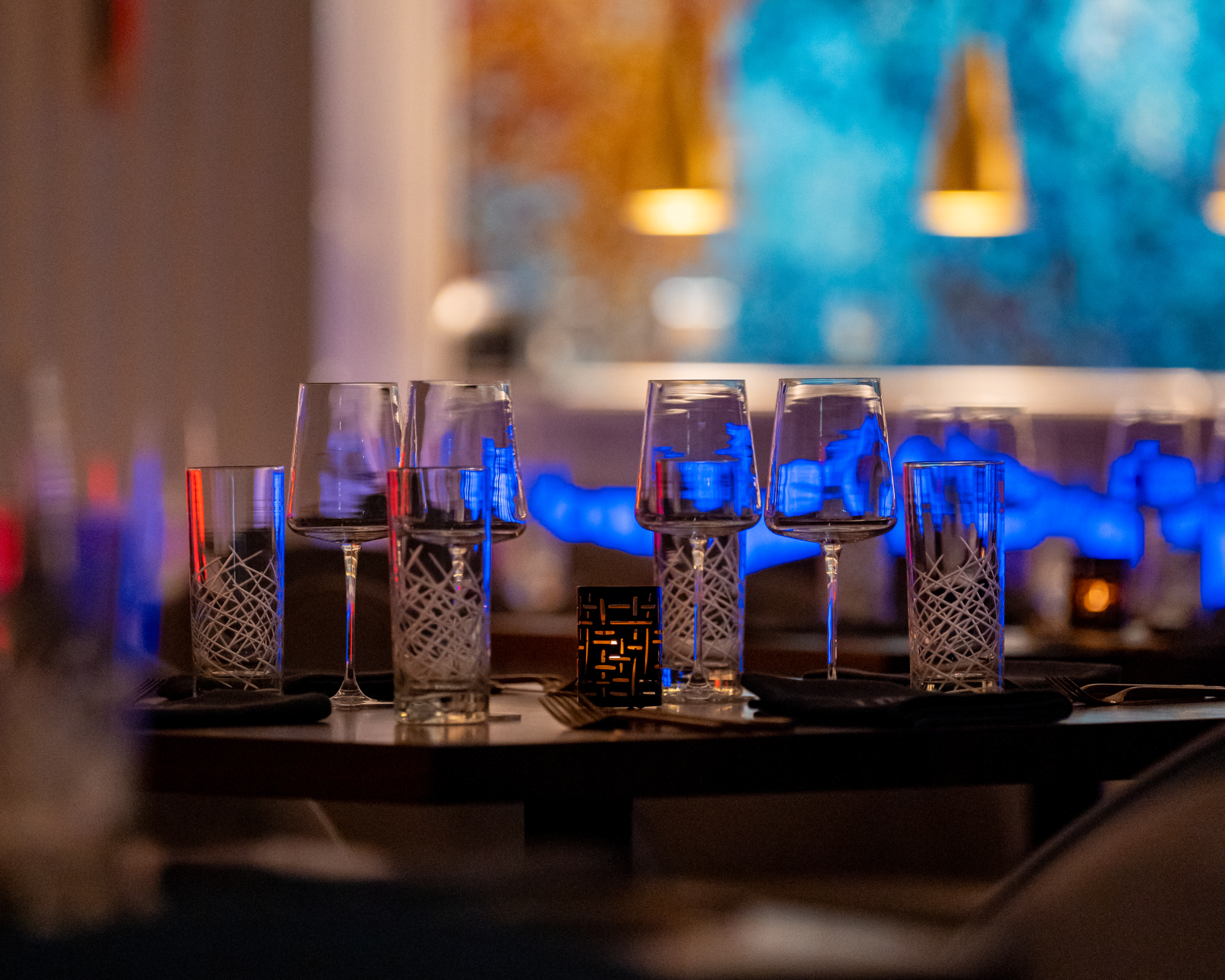 Empty wine and water glasses on a dimly lit restaurant table.